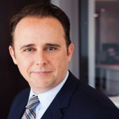 A man in suit and tie standing next to a window.