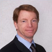 A man in suit and tie standing next to wall.